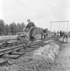 168477 Afbeelding van wegwerkers van de N.S. tijdens het leggen van spoor met zig-zag dwarsliggers in een spoorlijn op ...
